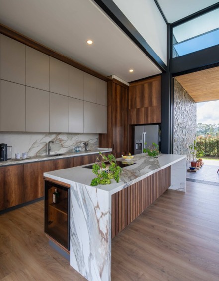 Cocina amplia y abierta con tonos madera y material de ascale