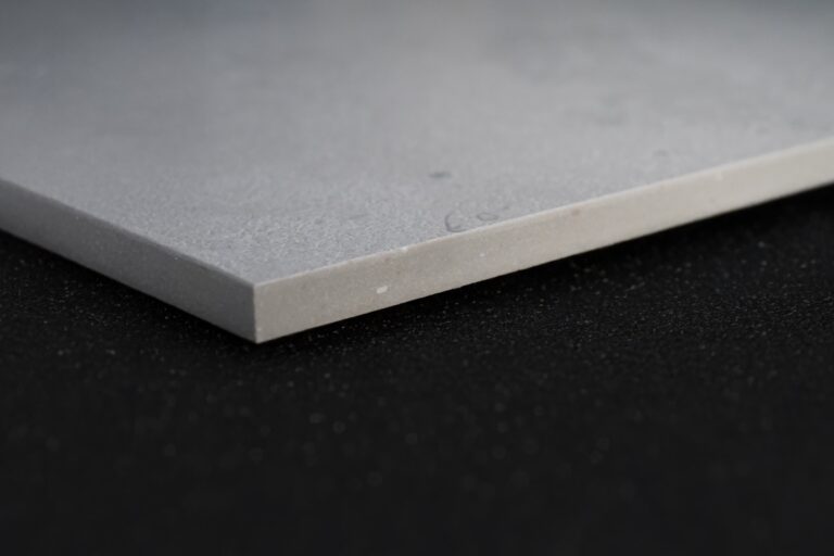 Plano cercano del canto de una losa de piedra sinterizada Portland Pearl, mostrando su grosor, textura mate y acabado realista que imita al concreto Portland.