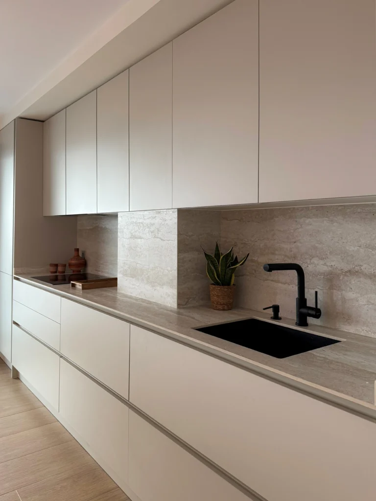 Cocina minimalista con muebles blancos y encimera de Tivoli White, pequeños objetos decorativos y salpicadero a juego.